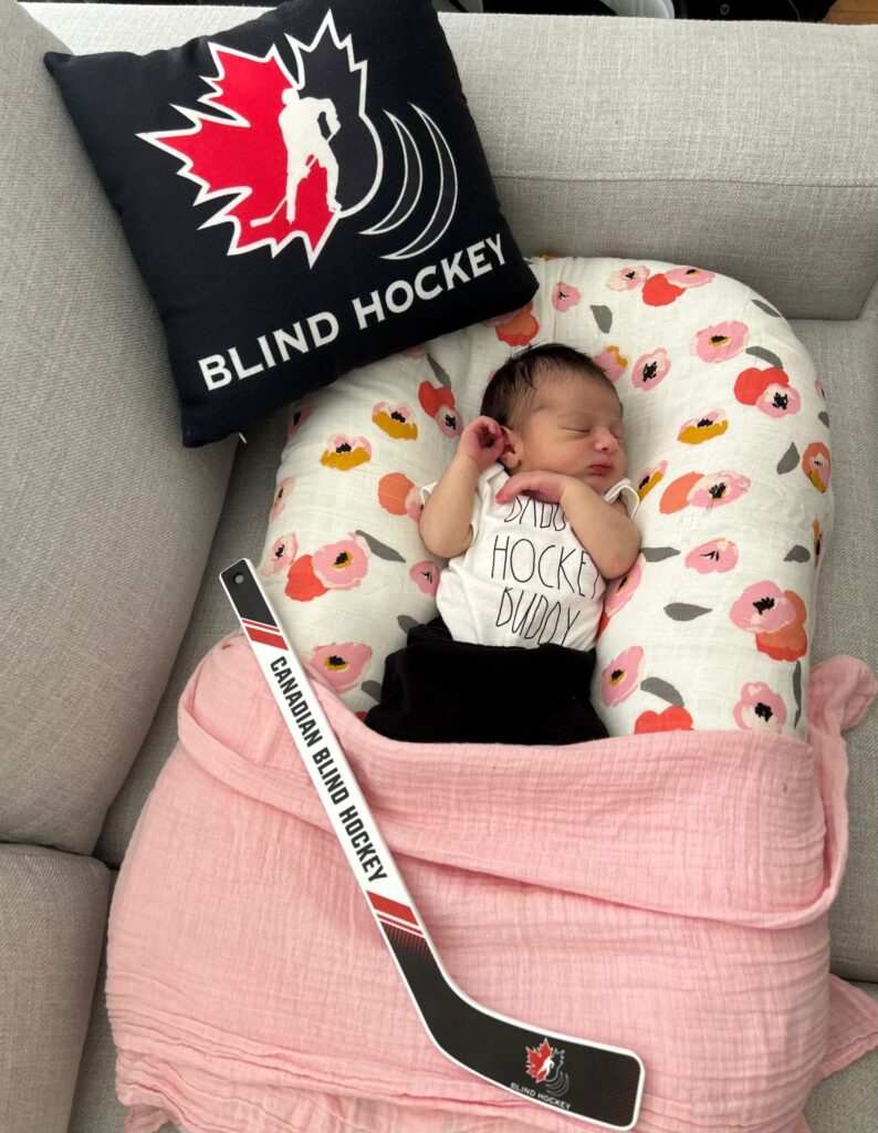 ébé bianca dort à côté d'un oreiller et d'un bâton de hockey avec notre logo